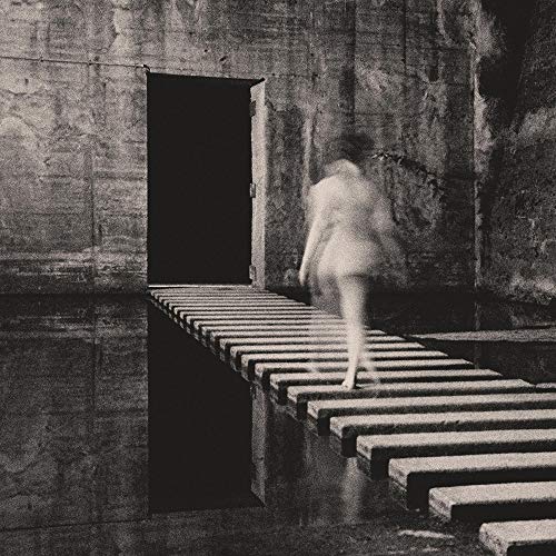 Black and white image of a person running on a grated bridge towards a dark doorway.