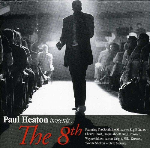Black and white image of man walking down runway, surrounded by seated audience.