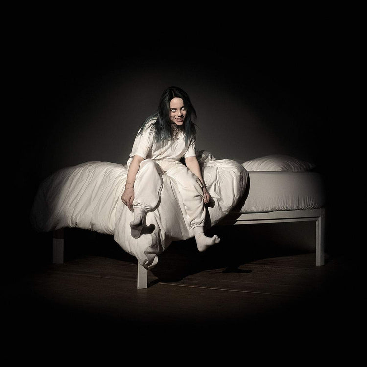 "Billie Eilish sitting on a bed with white sheets, wearing a white outfit."