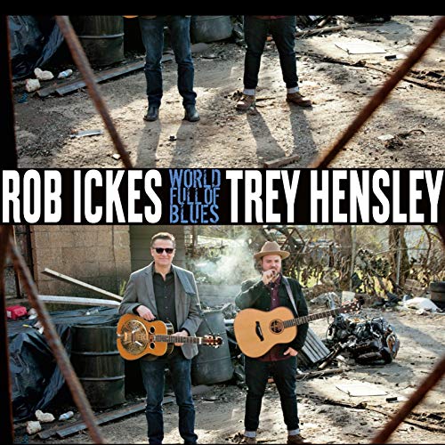 "Album cover featuring two men holding guitars in a junkyard setting."