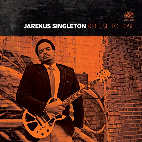 "Album cover featuring a man in a suit holding an electric guitar."
