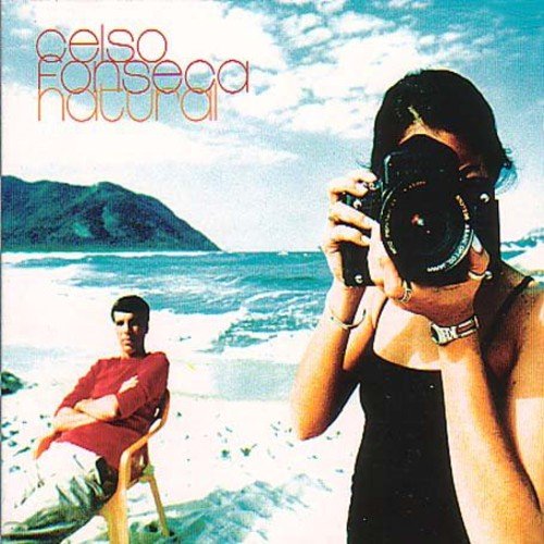 "Album cover with a man and woman on a beach, woman holding a camera."