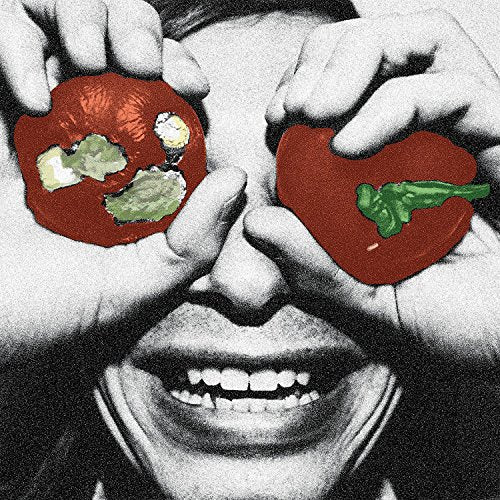 A person holds rotten tomatoes over their eyes, with a wide, toothy grin.