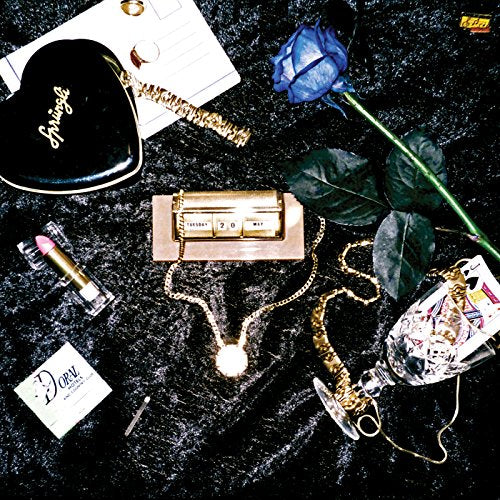 Compact disc surrounded by jewelry, makeup, and a blue rose on a black background.