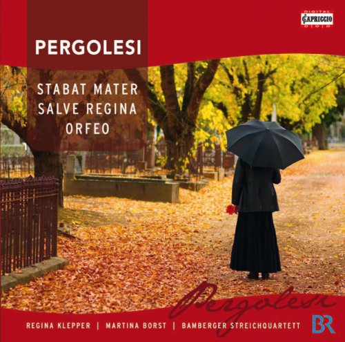 A woman in black holds an umbrella in a park with autumn leaves.