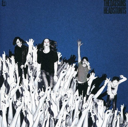 "Album cover with monochrome image of band on crowd, blue background, and 'The Datsuns' text."