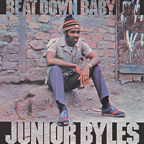 "Album cover featuring Junior Byles sitting against a brick wall, wearing casual attire."