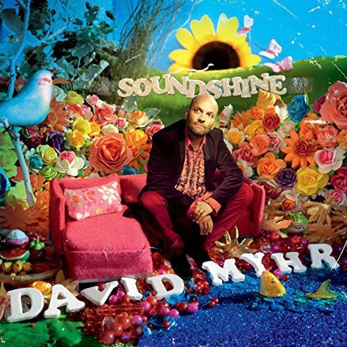 "Vinyl album cover with man sitting on a pink armchair surrounded by flowers."