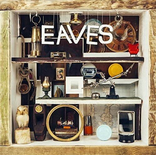 Album cover with "EAVES" text, featuring a wooden cabinet with various eclectic objects inside.