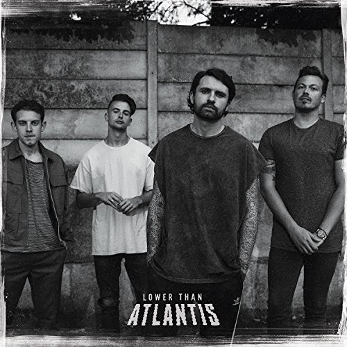 "Black and white album cover featuring four men standing against a wooden fence."