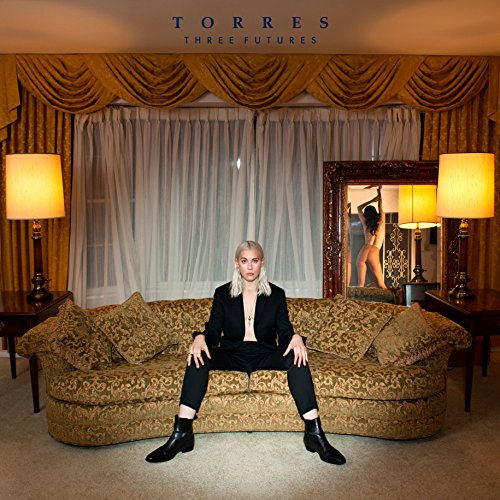 "Album cover: woman sitting on ornate sofa, with mirror reflection, in a luxurious room."