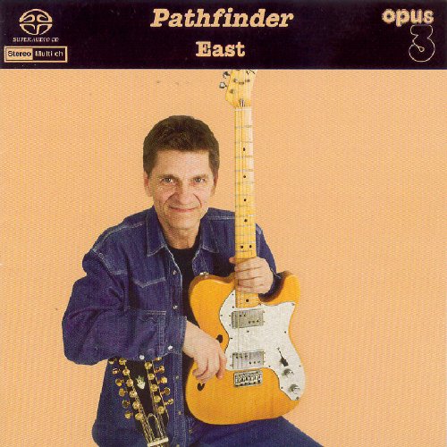 Man holding a light-brown electric guitar against a peach-colored background.