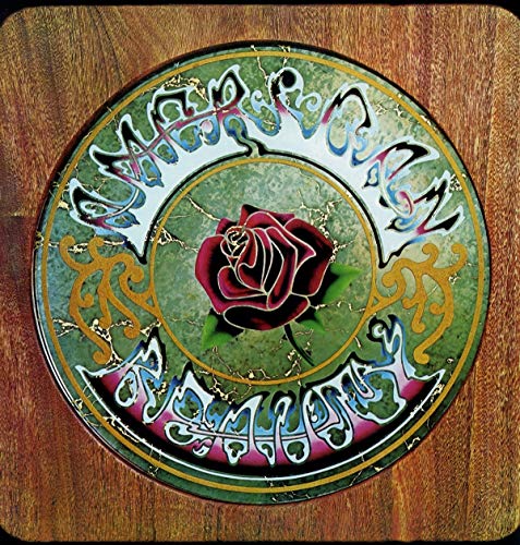 "Grateful Dead vinyl record cover with red rose on wooden background, ornate lettering."
