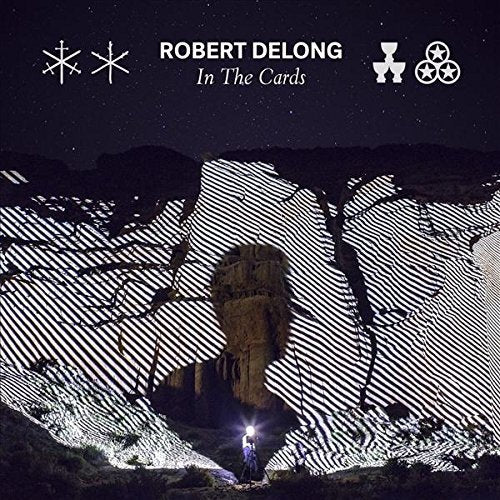 "Album cover for 'In The Cards' by Robert DeLong, featuring a person in a rocky landscape."