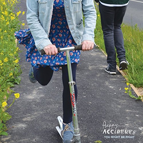 A girl rides a scooter on a path, with a person walking behind her.