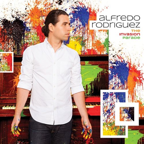 Man in white shirt stands before piano with paint splatters on hands and background.