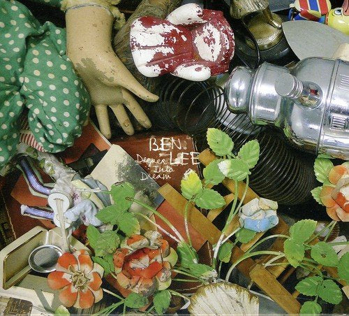 "Album cover with doll's hand, flowers, and various objects, titled 'Deeper Into Dream'."