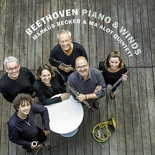 "CD cover featuring five musicians standing around a table, holding various instruments."