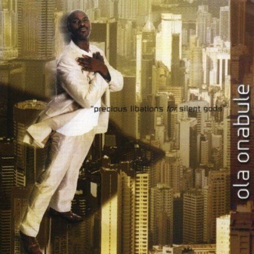 Album cover with man in white standing on skyscraper, cityscape background, artist's name on right.