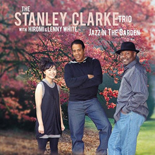 "Album cover featuring three musicians standing outdoors with a blooming tree behind them."