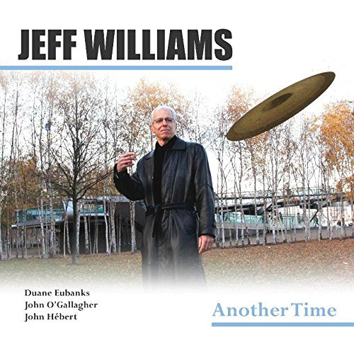 "Album cover with man in black coat tossing a CD in an outdoor setting."