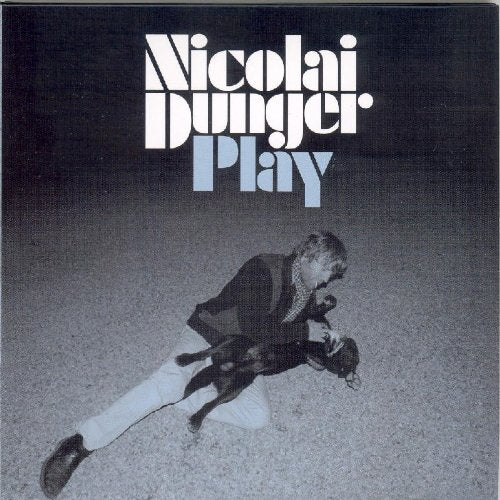 "Album cover with a man kneeling, holding a guitar, on a gravel surface."