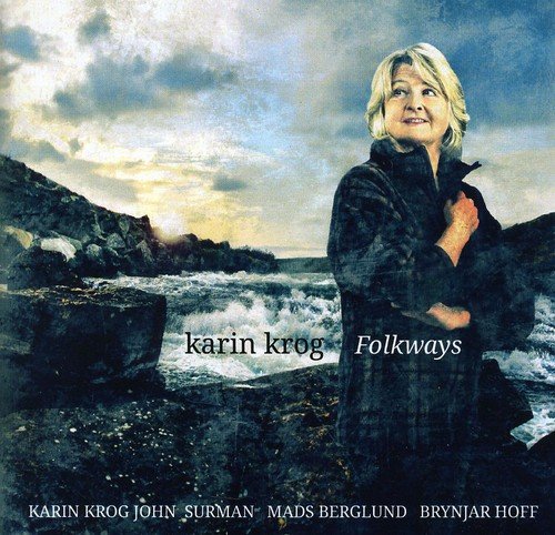 "CD cover featuring a blonde woman in a black coat by the ocean."