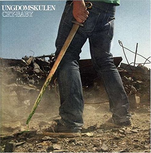 Album cover featuring a person in jeans holding a sword in a dusty landscape.
