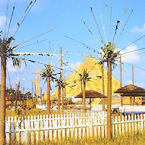 A white picket fence, palm trees, and a large yellow pyramid under a blue sky.