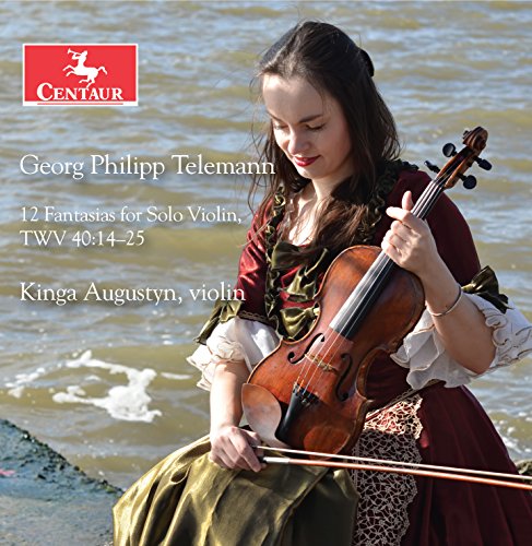 A woman in a red dress plays violin by a body of water.