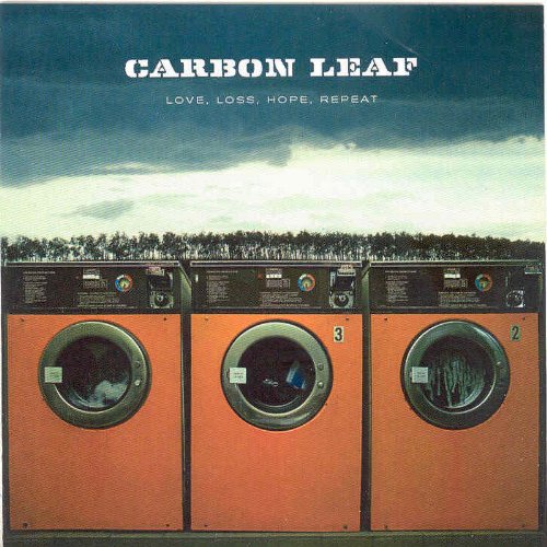 "Album cover with three orange washing machines and cloudy sky."