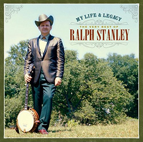The image depicts a man standing in a field, holding a banjo. The man is wearing a cowboy hat and a suit, and the background features trees and a clear sky. Alt text: "Man in cowboy hat and suit holding banjo in a field."