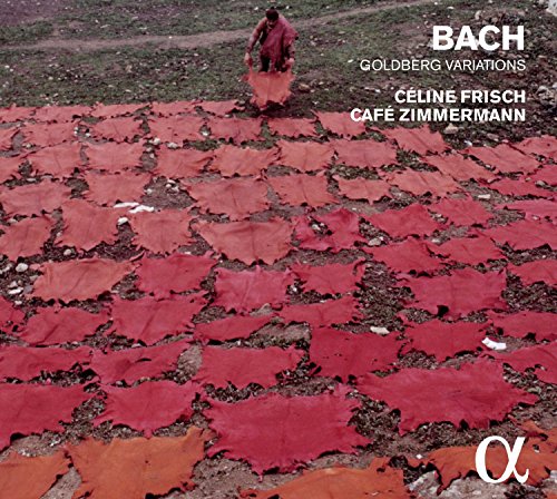"CD cover with red animal hides on ground and a person in the background."