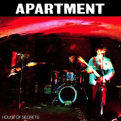 "Apartment" album cover featuring a dimly lit band performing on stage with red lighting.