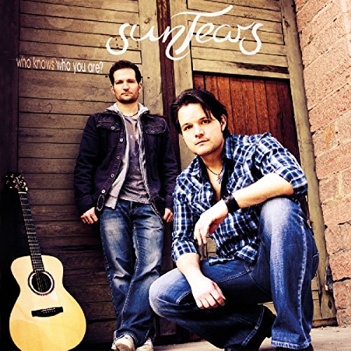 "Album cover with two men standing and crouching by a wooden door, with a guitar."