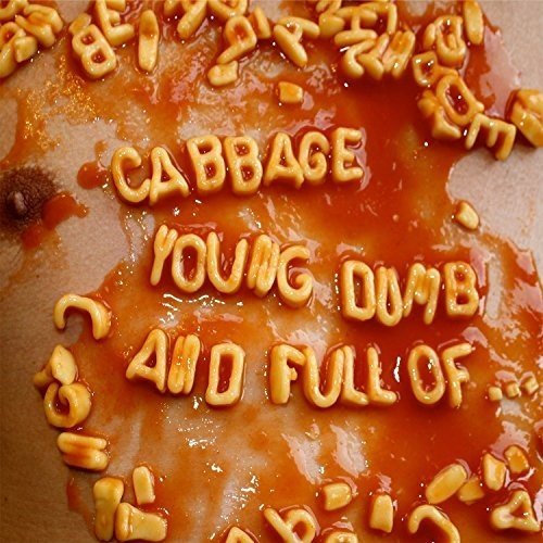 The image depicts a vinyl record with macaroni letters spelling out "Cabbage - Young, Dumb and Full Of...". For accessibility purposes, a suitable alt text could be: "Vinyl record with macaroni letters on a red sauce background."