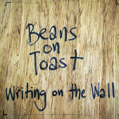 "Album cover with 'Beans on Toast' and 'Writing on the Wall' handwritten on a woodgrain background."
