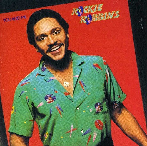 "Album cover featuring Rockie Robbins in a green shirt against a red background."