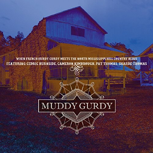 Album cover for "Muddy Gurdy" featuring a barn with ivy and a decorative logo.