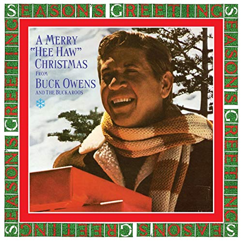 Buck Owens smiling, playing guitar, in a snowy scene, on a Christmas album cover.