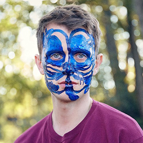 A man with blue face paint on, wearing a red t-shirt, outdoors.