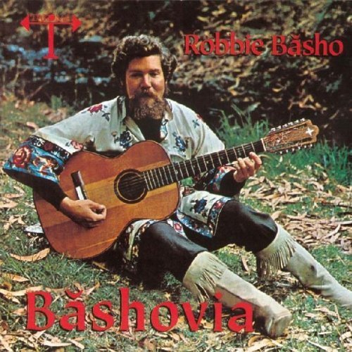 Man sitting on grass, holding acoustic guitar, with red text overlay on album cover.