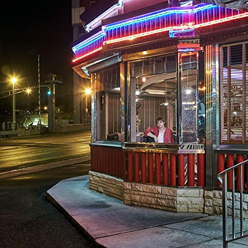 The alt text for the image is: "A woman inside a diner at night."