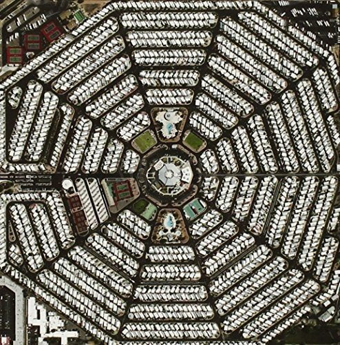 The alt text for the image is: "Aerial view of a circular housing development with symmetrical white buildings."