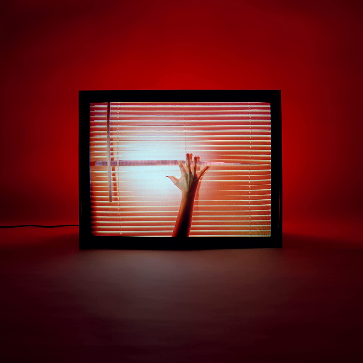 A vinyl record sleeve with a hand reaching through window blinds, lit red.
