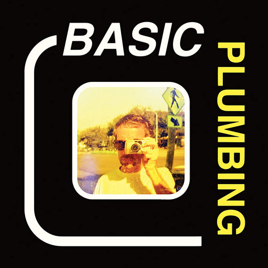 The image depicts a man holding a camera, surrounded by text on a black background. For accessibility purposes, a concise alt text could be: "Man holding camera, surrounded by 'BASIC PLUMBING' text on black background."