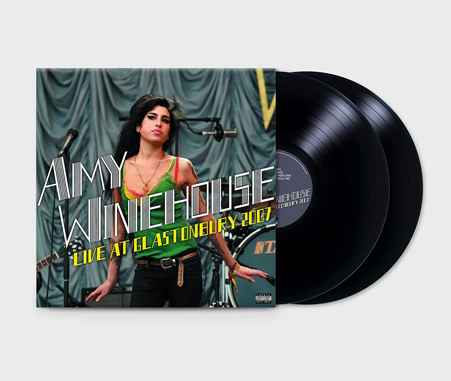 Amy Winehouse on stage, wearing a green top, with superimposed text and a microphone.